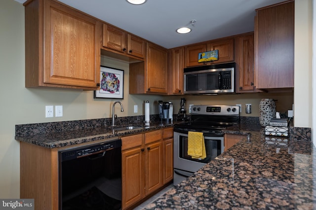 kitchen featuring stainless steel appliances, dark stone countertops, and sink