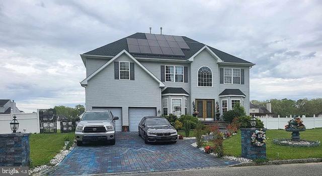 view of front facade featuring a garage, solar panels, and a front yard