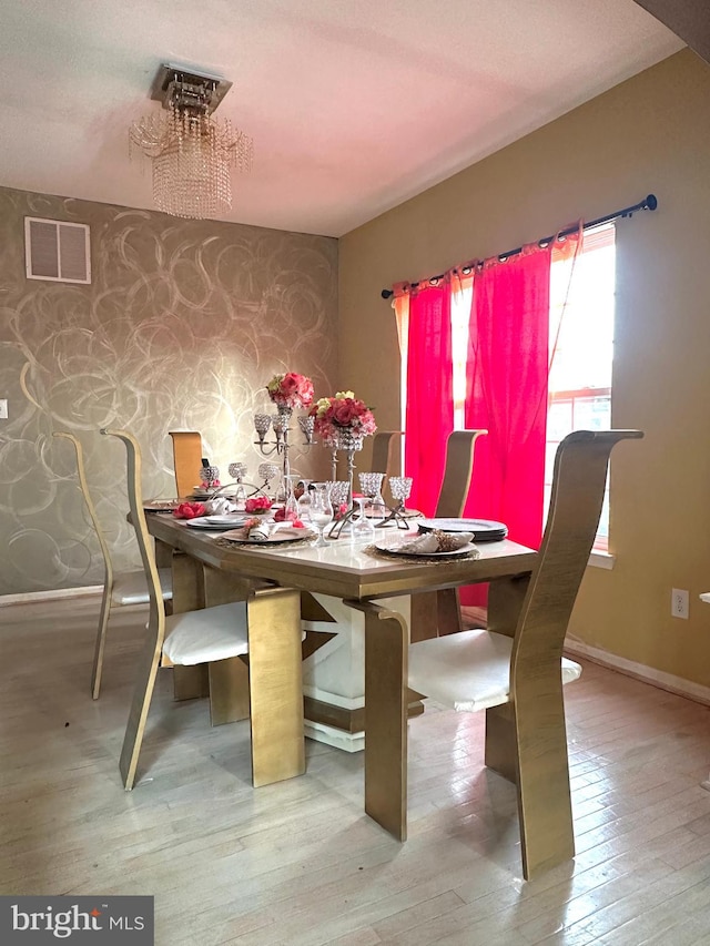 unfurnished dining area featuring light wood-type flooring and a notable chandelier