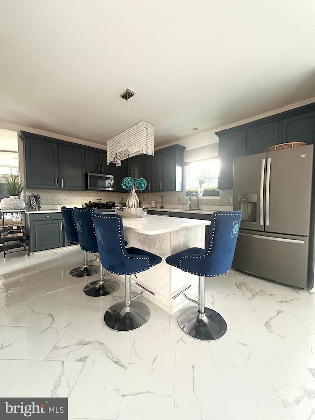 kitchen with a kitchen bar, hanging light fixtures, sink, tasteful backsplash, and appliances with stainless steel finishes