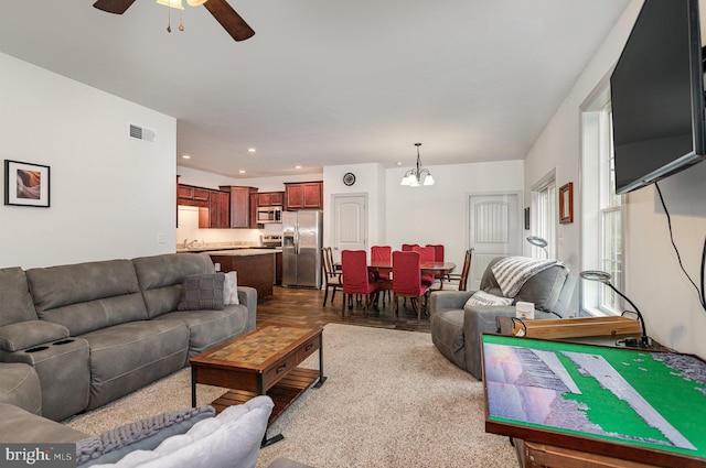 living room with sink, ceiling fan with notable chandelier, and hardwood / wood-style floors