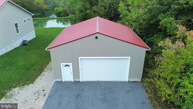 garage with a water view, a yard, and central air condition unit