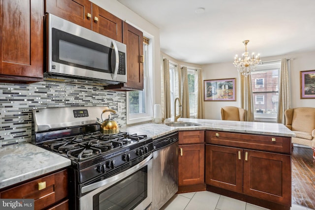 kitchen featuring stainless steel appliances, light wood-type flooring, kitchen peninsula, and a healthy amount of sunlight