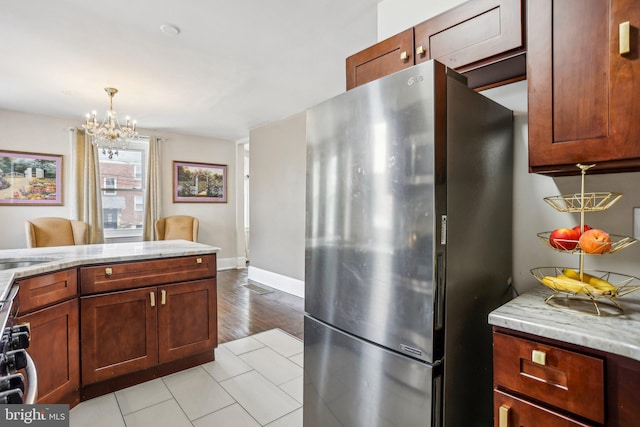 kitchen featuring pendant lighting, light stone countertops, stainless steel fridge, and light hardwood / wood-style floors