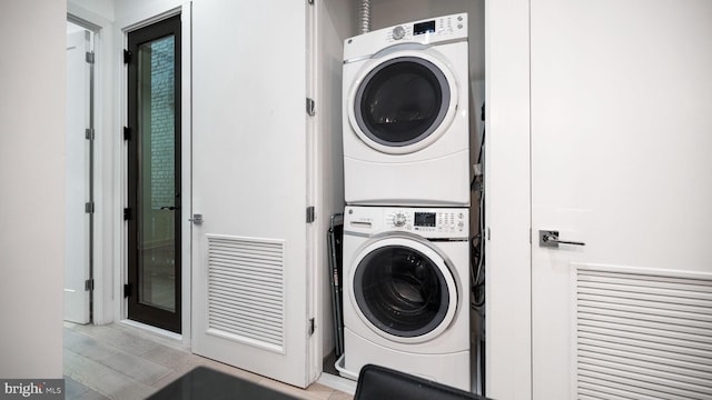 clothes washing area with stacked washing maching and dryer