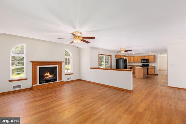 unfurnished living room featuring ceiling fan and light wood-type flooring