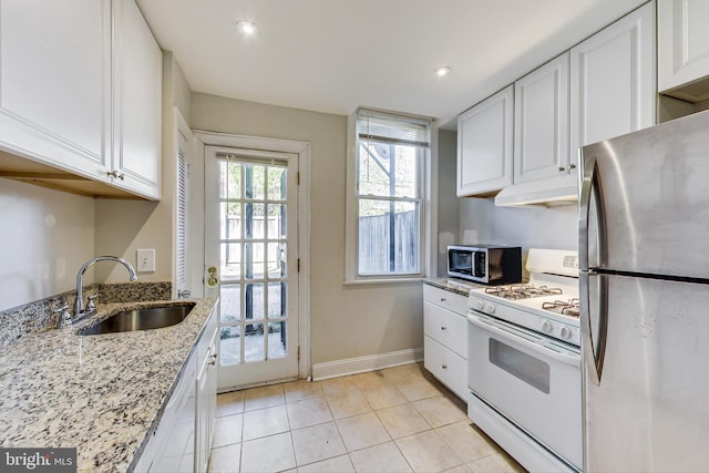 kitchen with white cabinetry, appliances with stainless steel finishes, light stone counters, and sink