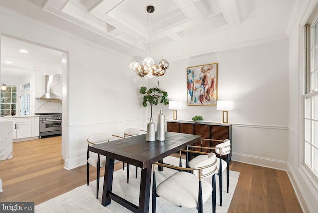 dining space with light hardwood / wood-style flooring, coffered ceiling, and ornamental molding