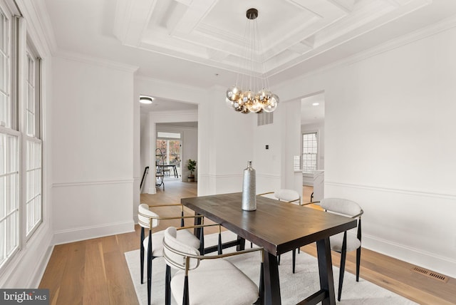 dining room with crown molding, light hardwood / wood-style floors, coffered ceiling, and a notable chandelier