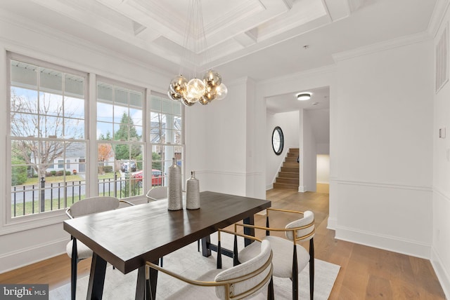 dining space with a notable chandelier, light wood-type flooring, ornamental molding, and coffered ceiling