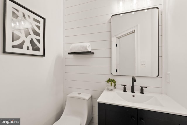 bathroom featuring vanity, toilet, and wood walls