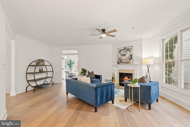 living room featuring light wood-type flooring, plenty of natural light, and ornamental molding