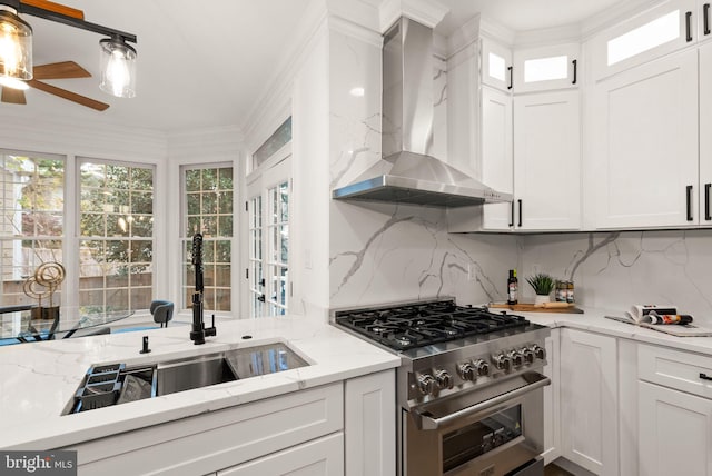 kitchen with white cabinets, high end stove, and wall chimney range hood