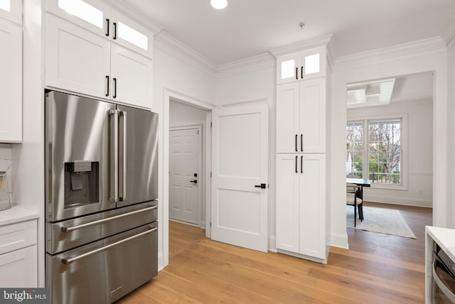 kitchen with high end refrigerator, light hardwood / wood-style flooring, white cabinets, and ornamental molding