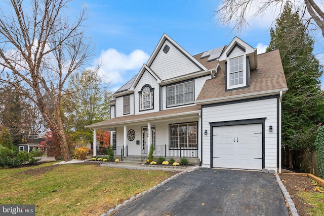 view of front of home featuring a front yard, a garage, a porch, and solar panels