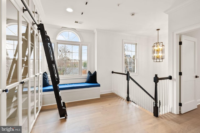 interior space featuring a notable chandelier, ornamental molding, and light hardwood / wood-style flooring