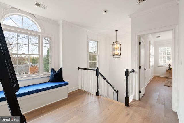 hall featuring plenty of natural light, crown molding, a chandelier, and light hardwood / wood-style flooring