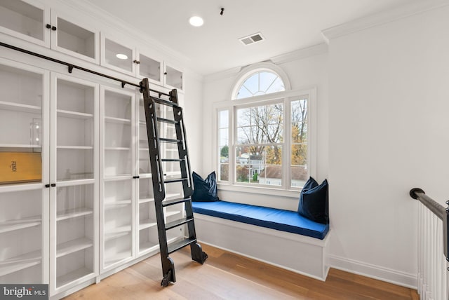 living area featuring crown molding and hardwood / wood-style flooring