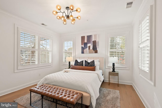 bedroom featuring multiple windows, crown molding, light hardwood / wood-style floors, and an inviting chandelier