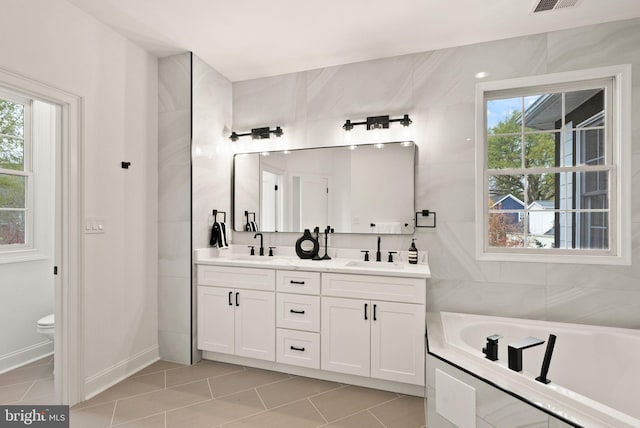 bathroom with a bathing tub, tile patterned flooring, vanity, and toilet