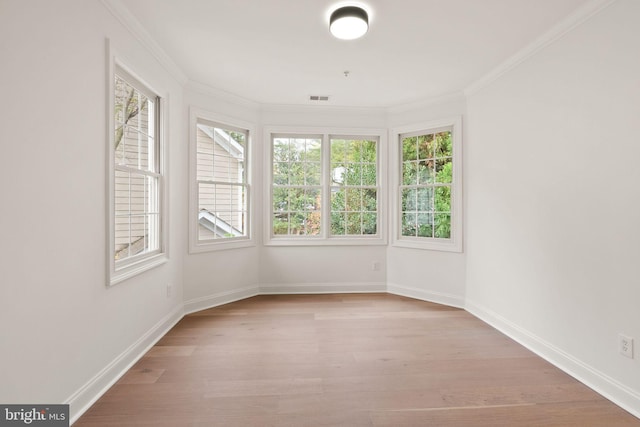 empty room with ornamental molding and light hardwood / wood-style flooring