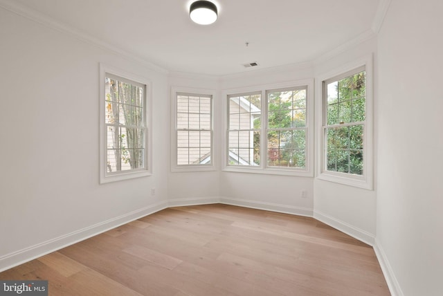 unfurnished room with a wealth of natural light, light hardwood / wood-style flooring, and ornamental molding