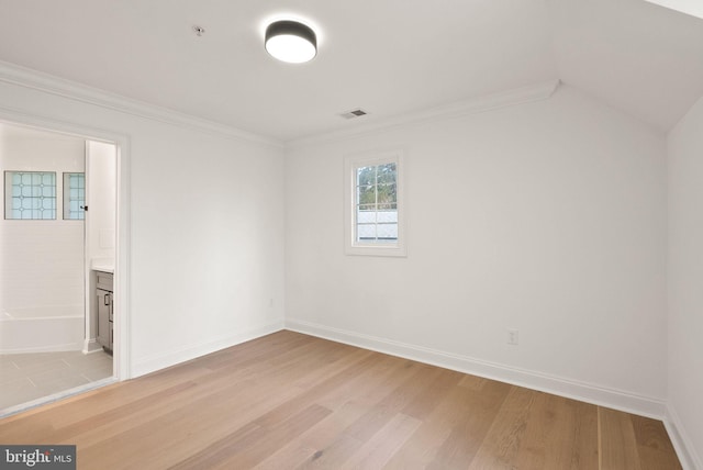 spare room featuring lofted ceiling, light hardwood / wood-style flooring, and crown molding