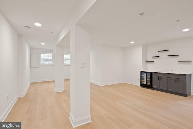 bar with gray cabinets, sink, beverage cooler, and light wood-type flooring