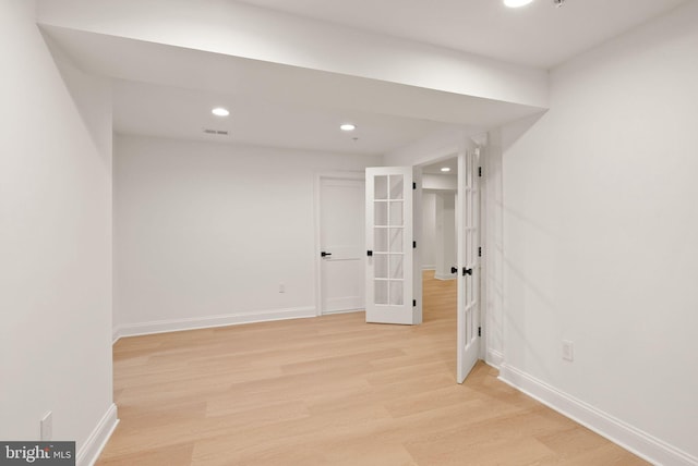 basement featuring french doors and light hardwood / wood-style floors