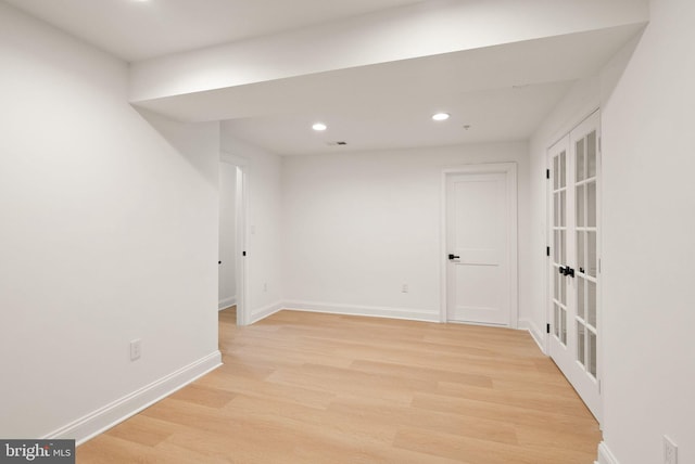 spare room with french doors and light hardwood / wood-style flooring