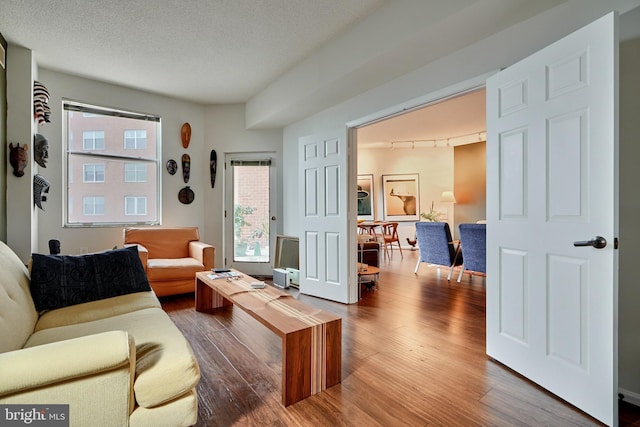 living room featuring a textured ceiling, track lighting, and hardwood / wood-style flooring