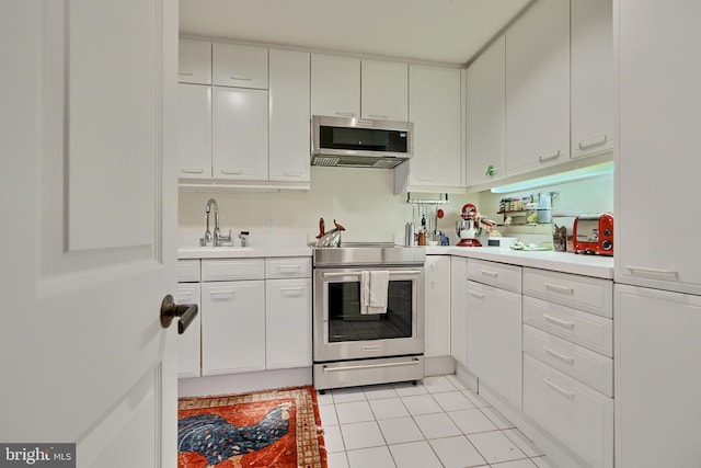 kitchen featuring light tile patterned flooring, sink, stainless steel appliances, and white cabinets