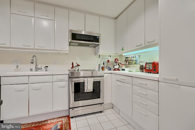 kitchen with light tile patterned flooring, appliances with stainless steel finishes, sink, and white cabinetry