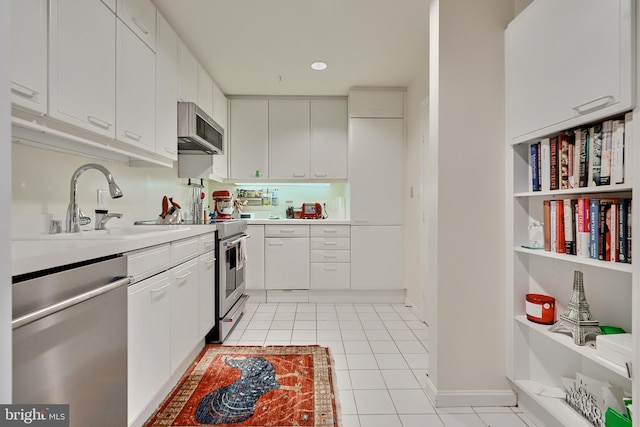 kitchen with stainless steel appliances, white cabinets, light tile patterned floors, and sink