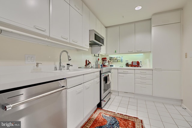 kitchen with light tile patterned flooring, sink, stainless steel appliances, and white cabinets