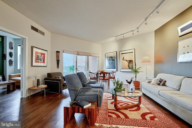 living room featuring rail lighting, a textured ceiling, and dark hardwood / wood-style flooring