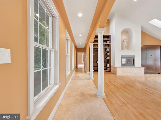 hallway with lofted ceiling, light hardwood / wood-style floors, and ornate columns