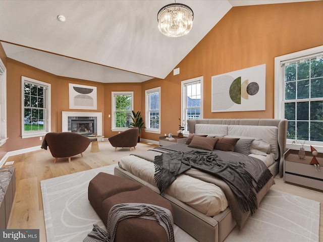 bedroom featuring light wood-type flooring, high vaulted ceiling, and an inviting chandelier