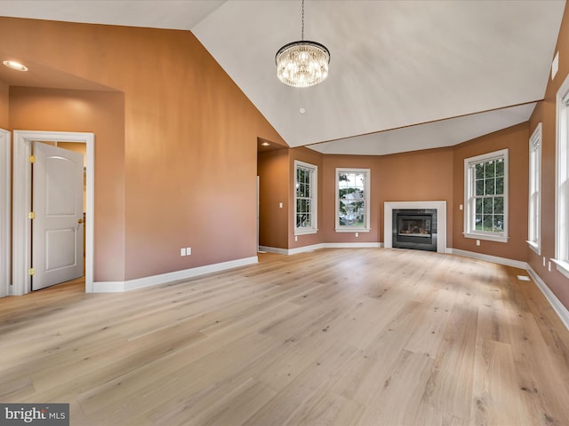 52 Violets Path, Elizabethtown, PA 17022 - unfurnished living room featuring baseboards, a chandelier, a glass covered fireplace, high vaulted ceiling, and light wood-type flooring