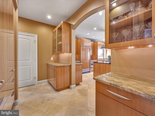 52 Violets Path, Elizabethtown, PA 17022 - kitchen featuring arched walkways, light stone countertops, glass insert cabinets, recessed lighting, and brown cabinets