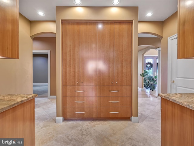 52 Violets Path, Elizabethtown, PA 17022 - kitchen with arched walkways, light stone counters, brown cabinets, and baseboards