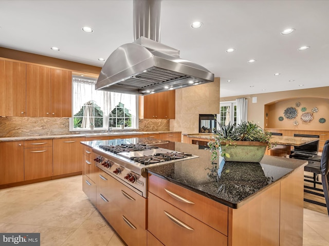 kitchen featuring dark stone countertops, island range hood, a spacious island, and stainless steel gas cooktop