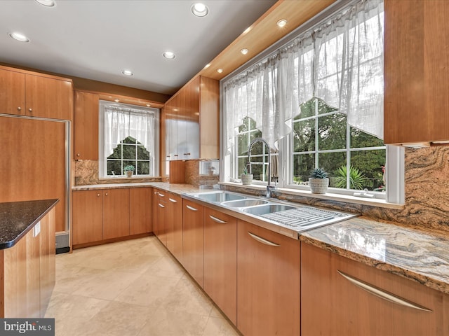 kitchen with paneled built in fridge, light tile patterned floors, stone counters, and tasteful backsplash