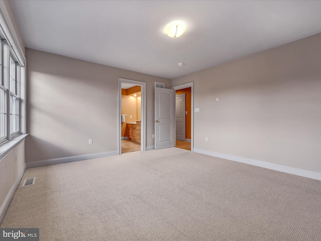 unfurnished bedroom with light carpet and connected bathroom