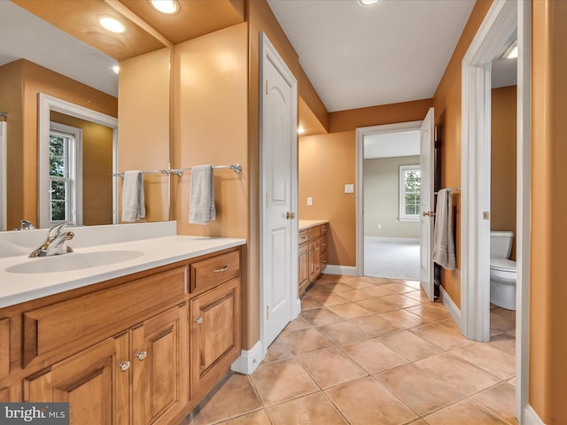 bathroom with tile patterned floors, vanity, toilet, and a healthy amount of sunlight