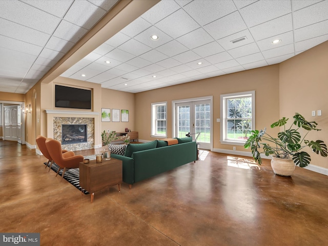 living room featuring a paneled ceiling, french doors, a high end fireplace, and concrete floors