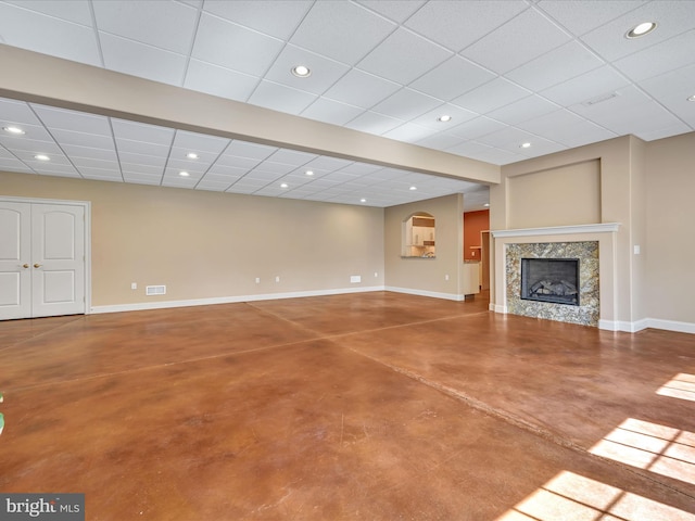 unfurnished living room with a high end fireplace, concrete floors, and a paneled ceiling