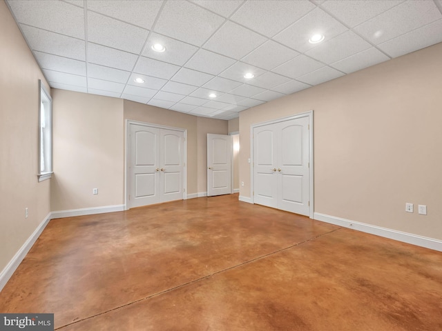 unfurnished bedroom with a paneled ceiling and concrete floors