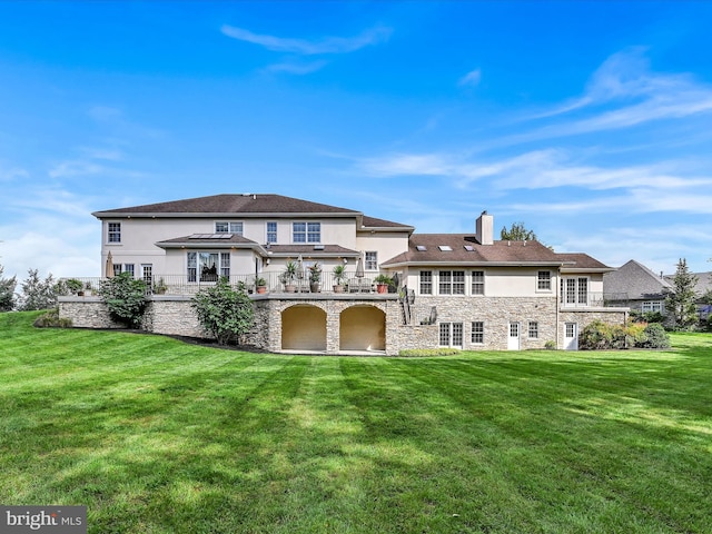 rear view of property with a yard and a balcony