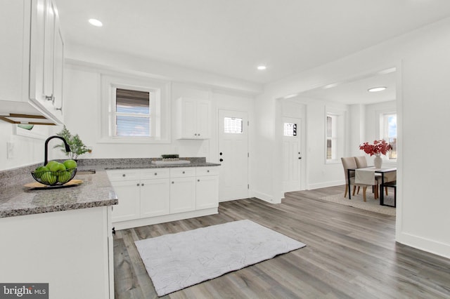 kitchen with a healthy amount of sunlight, wood-type flooring, and white cabinetry